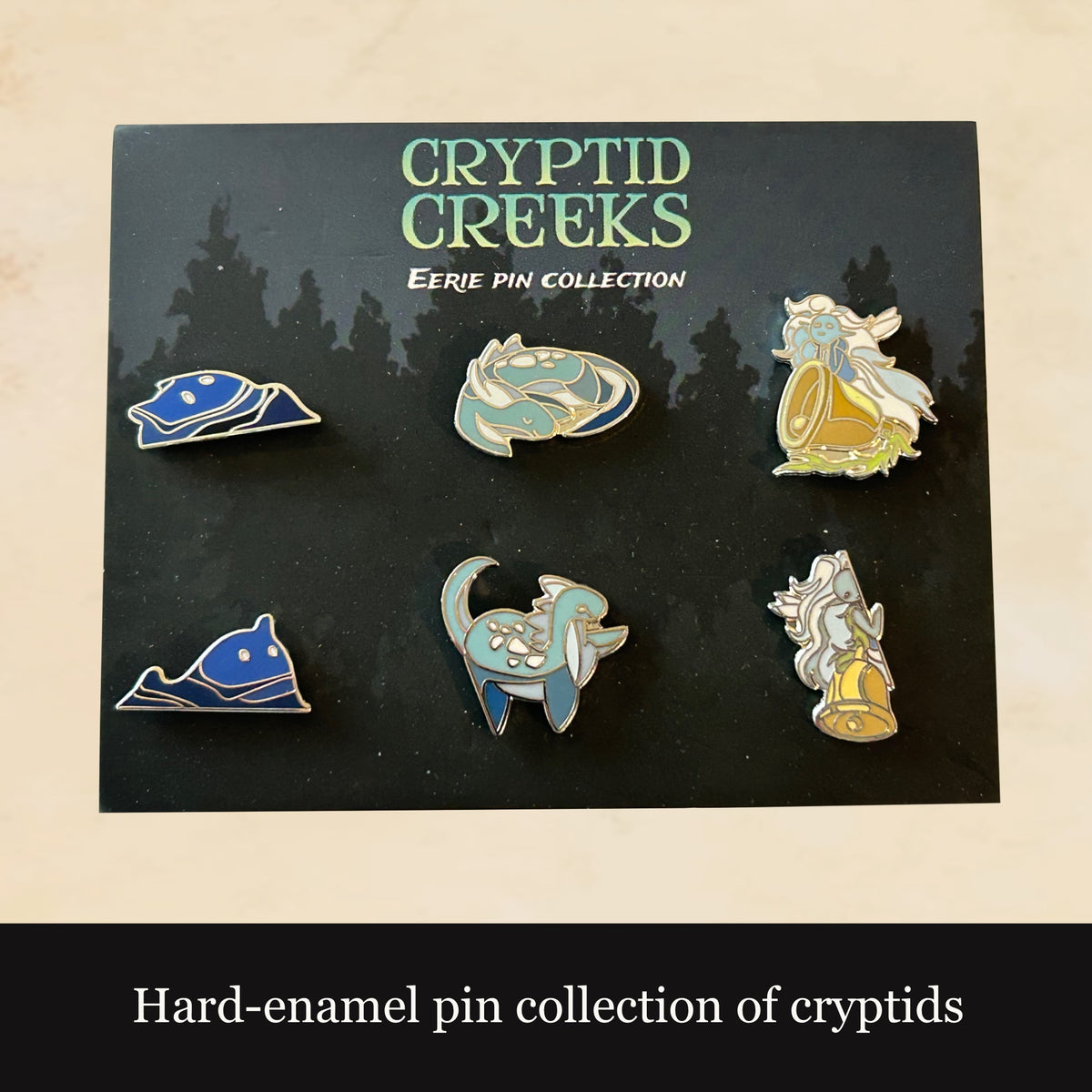 Collection of hard-enamel pins featuring cryptids on a 'Cryptid Creeks' card.